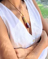 Collar con dije de cuarzo transparente facetado, engarzado en metal plateado y colgante de tiento de cuero marrón.