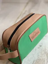 Necessaire de lona color naranja con detalles en cuero y cierre superior.