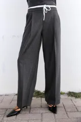 Pantalón ancho gris con textura de espiga, tiro alto, doble cintura elástica ajustable con cordón, pinzas frontales, bolsillos delanteros y falso bolsillo de vivo en la espalda.