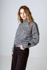 Sweater de punto jaspeado en blanco y negro, con cuello alto y mangas largas abullonadas.