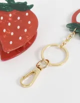 Set de accesorios para el pelo que incluye un broche de pelo con forma de fresa y un llavero con espejo con forma de fresa.