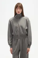 Campera gris de manga larga con cierre frontal, cuello alto y vivos blancos en los hombros y mangas.