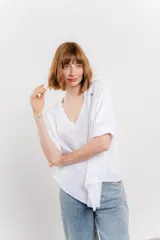 Blusa color naranja confeccionada en 100% lino, con escote en V, mangas cortas con vuelta y silueta amplia. Presenta terminación asimétrica y fila de botones decorativos en uno de los hombros.