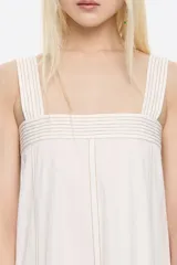 Vestido largo midi de corte línea A, color blanco, confeccionado en mezcla de lino. Presenta escote recto, tirantes anchos, fruncido en la espalda, bolsillos plastrón tipo alforja y pespuntes a contraste en toda la prenda.