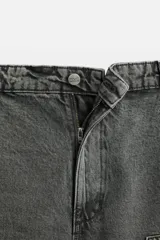 Pantalón color marrón con efecto lavado, corte relaxed fit, cinco bolsillos, aplicación de tira y bolsillo multifunción en perneras, cierre frontal con cremallera y botón.