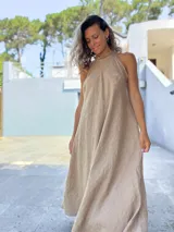 Vestido largo color habano, de corte amplio y fluido, con escote halter que se ata en la nuca.