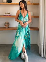 Vestido largo de tela fluida, color verde esmeralda con estampado abstracto en tonos turquesa y detalles dorados. Diseño asimétrico con un solo tirante tejido en el hombro.