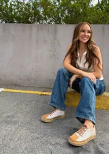 Championes deportivos de cuero vacuno, color beige con detalles en marrón tostado y cordones marrones. Tienen una suela de goma de 2,5 cm de altura en la parte trasera y 1,5 cm en la delantera, con una inclinación de 1 cm. La horma es de punta redonda, ancha y cómoda.