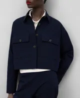 Chaqueta corta azul marino de algodón seersucker con cuello solapa, manga larga con puño abotonado, cierre frontal con botones y bolsillos con solapa y botón en el delantero.