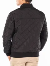 Campera bomber negra Calvin Klein con diseño acolchado en forma de rombos, cierre frontal con cremallera, cuello, puños y dobladillo acanalados, bolsillos laterales y bolsillo con cremallera en la manga izquierda.