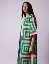 Cardigan largo tejido al crochet con diseño geométrico en verde y rosa. Tiene mangas 3/4 y corte holgado.