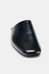 Zapato plano destalonado de piel color negro, con punta redonda y suela de 1,5 cm.