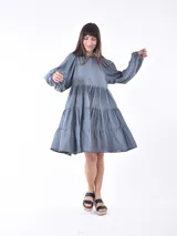 Vestido corto negro con mangas globo abullonadas y cuello redondo. El cuerpo del vestido es ajustado y la falda tiene un corte en capas con volados.