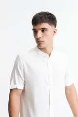 Camisa blanca de manga corta con cuello mao y doblez en las mangas.
