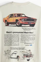 Remera color crema de corte holgado con estampado de un caballo Mustang y el año 1970 en el pecho. Cuello redondo con ribete fino y hombros caídos.