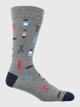 Calcetín de largo medio, color gris jaspeado, con motivos relacionados a la barbería como tijeras, peines, máquinas de afeitar, barber pole y bigotes. El talón y la punta son de color azul marino.