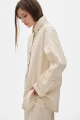 Camisa de jean color crudo, corte oversized, con botones rojos y pespuntes a contratono.