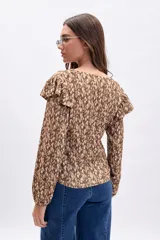 Blusa de manga larga con cuello en V y volados en los hombros. Presenta un estampado abstracto en tonos marrones y rosados claros.