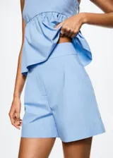 Short celeste de algodón con tiro alto, diseño recto, detalle de pinzas, bolsillos laterales y traseros decorativos. Cierre frontal con botón, gancho y cremallera.