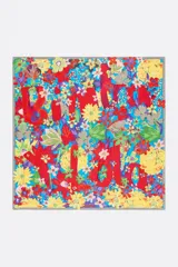 Pañuelo cuadrado de poliéster reciclado con estampado floral multicolor y logo en acuarela sobre fondo celeste.