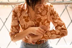 Camisa de manga larga color marrón con estampado de flores rosas.