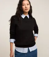Sweater negro de punto con cuello redondo, puños y ruedo acanalados. Incluye cuello, puños y ruedo de camisa celeste a rayas.