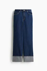 Jean de tiro superalto con pierna amplia y corte holgado. Presenta un diseño de cinco bolsillos, cierre con botón y un doblez ancho en el bajo que deja ver el revés de la tela. Confeccionado en denim con estampado de rayas finas verticales.