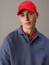 Gorra de béisbol roja con visera curva, confeccionada en algodón. Presenta el logo de Calvin Klein Jeans bordado en el frente en color azul.