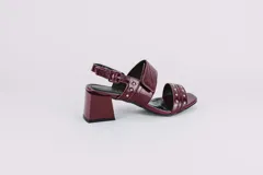 Sandalias de cuero con estampado animal print de vaca en blanco y negro, con detalles de tachas plateadas. Tienen correa trasera con hebilla y taco cuadrado de 5 cm.