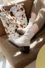 Bota corta de gamuza color beige claro, con caña ajustada y taco cuadrado de madera oscura.