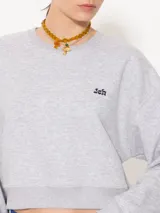 Buzo gris melange de rústico, con escote redondo, mangas largas, puños y cintura en tela complemento. Tiene un bordado de hongo y logo JCH.