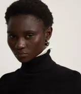 Blusa de punto color blanco, con cuello alto, manga larga y diseño liso.