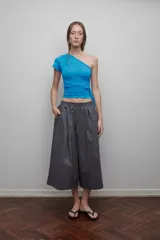 Top de manga corta asimétrico, color azul brillante, con escote cruzado y frunces en el torso.