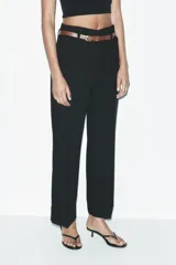 Pantalón marrón de tiro alto con cinturón negro, bolsillos delanteros y cierre frontal con cremallera y gancho metálico.