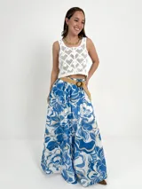 Falda larga de algodón con estampado floral en tonos marrón y blanco. Tiene elástico en la cintura y viene con un cinto de rafia elastizado desmontable.