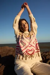 Sweater de punto color crudo con diseño geométrico en tonos marrón, rosa y lila. De corte holgado, manga larga y cuello redondo.