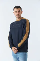 Buzo de felpa azul marino con cuello redondo y puños. Tiene mangas largas y calce regular. Presenta un logo estampado en relieve en el pecho y un logo de goma en la manga.