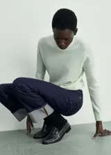 Pantalón de jean azul oscuro de corte recto con ruedo con dobladillo gris. Diseño de tiro medio, cinco bolsillos y cierre frontal con cremallera y botón.