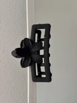 Broche para el pelo negro con forma rectangular y aplique de flor.