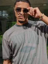 Remera de jersey con efecto teñido y corte holgado. Presenta una estampa frontal con el texto 'Sunset Lover' y 'You're my last sunburn' en color verde.