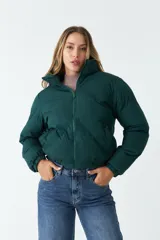 Campera puffer verde oscuro de nylon, con cuello alto, cierre frontal con cremallera, bolsillos laterales y cintura ajustable con cordón.