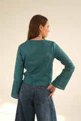 Blusa blanca de lino con escote en V cruzado, mangas largas y lazo en la cintura.