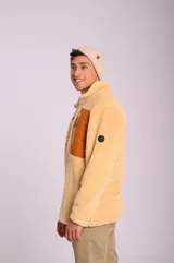 Buzo color beige de poliéster con textura tipo sherpa, cuello alto con cierre medio, bolsillo tipo parche en el pecho de color naranja con cierre vertical y puños con elástico.