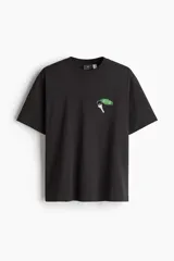 Remera negra de corte holgado y mangas cortas, con cuello redondo y estampado pequeño de llave de hotel en el pecho.