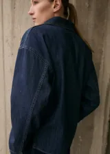 Camisa de jean azul oscuro, de corte holgado, manga larga y cuello clásico con abertura en V.