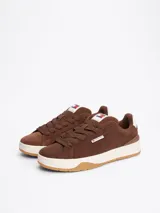 Zapatillas Tommy Jeans de corte bajo, color marrón, confeccionadas en gamuza con interior de poliéster y suela de goma. Presentan cordones, entresuela texturizada, etiqueta de la marca en el lateral y parche en la lengüeta.