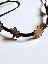 Gargantilla negra con apliques de flores doradas y tiras para atar.