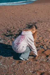 Hoodie rosa con capucha y cordones ajustables. Estampado en la espalda con un diseño de ondas, sol, concha marina y flores de hibisco.