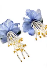 Par de aros con forma de flor celeste y cuentas blancas y amarillas colgantes.