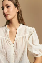 Camisa de manga corta abullonada con terminación elastizada, cuello con leve frunce y calce recto. Presenta una estampa floral integral sobre fondo claro.